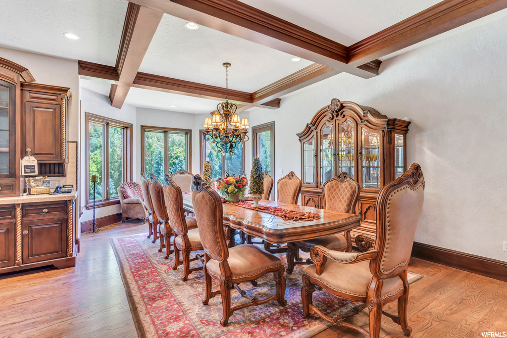 Hardwood floored dining space featuring a chandelier, coffered ceiling, and beam ceiling