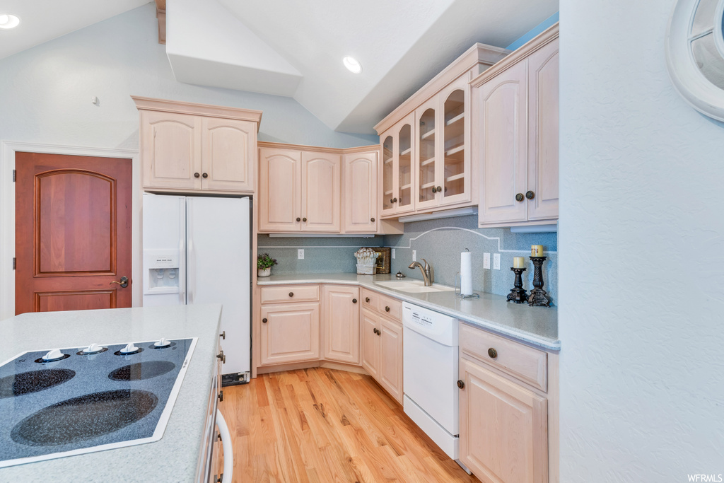 Kitchen featuring sink, vaulted ceiling, light hardwood floors, tasteful backsplash, and white appliances