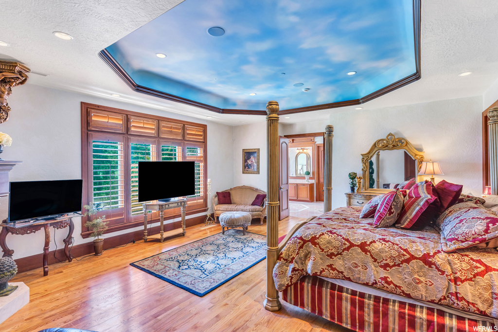 Bedroom with a tray ceiling and light hardwood flooring