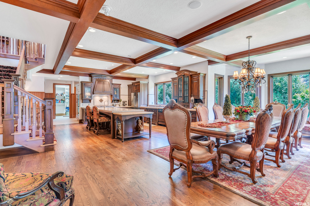 Wood floored dining area featuring a chandelier, coffered ceiling, and beamed ceiling