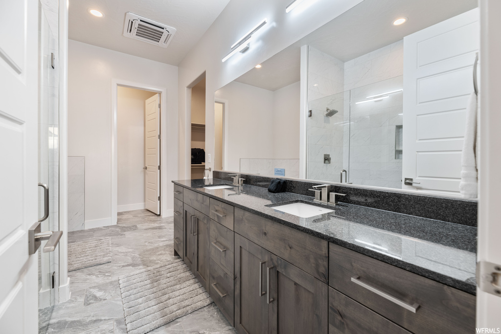 Bathroom featuring double vanity, tile floors, and walk in shower