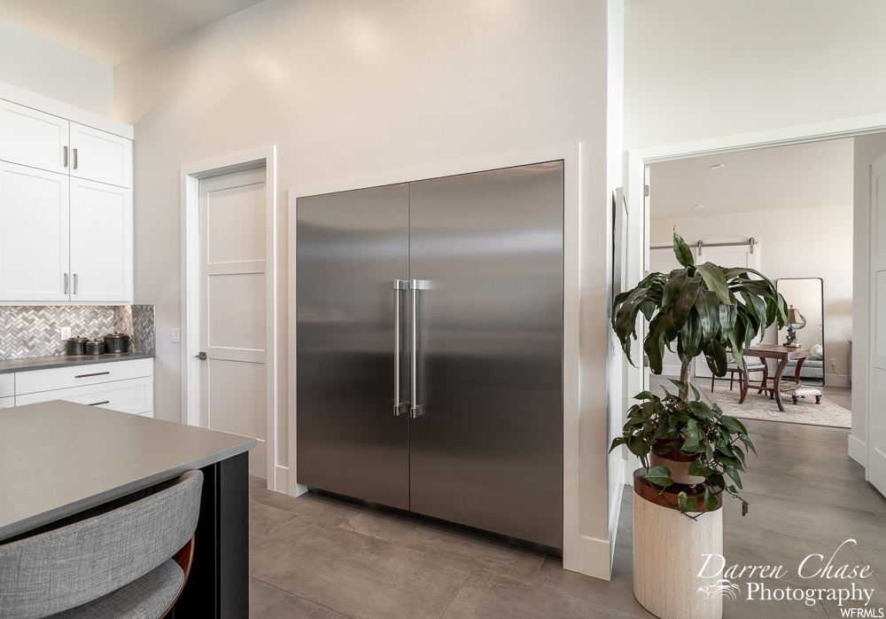 Kitchen featuring white cabinetry, built in refrigerator, light tile floors, and tasteful backsplash