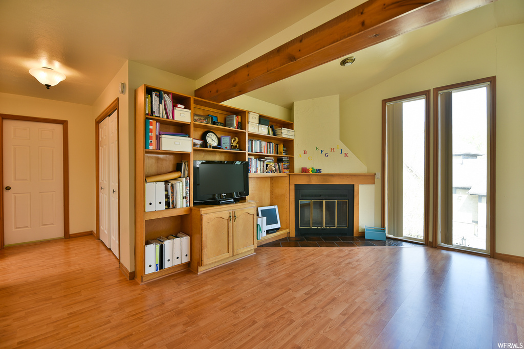 Unfurnished living room featuring hardwood flooring, a fireplace, and a wealth of natural light