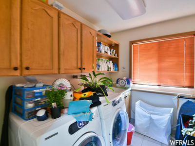 Clothes washing area featuring washer and clothes dryer and light tile floors