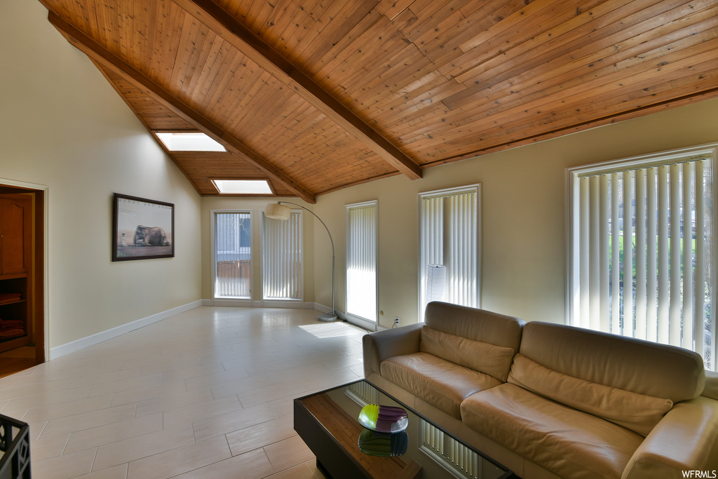 Tiled living room with vaulted ceiling with skylight and wood ceiling