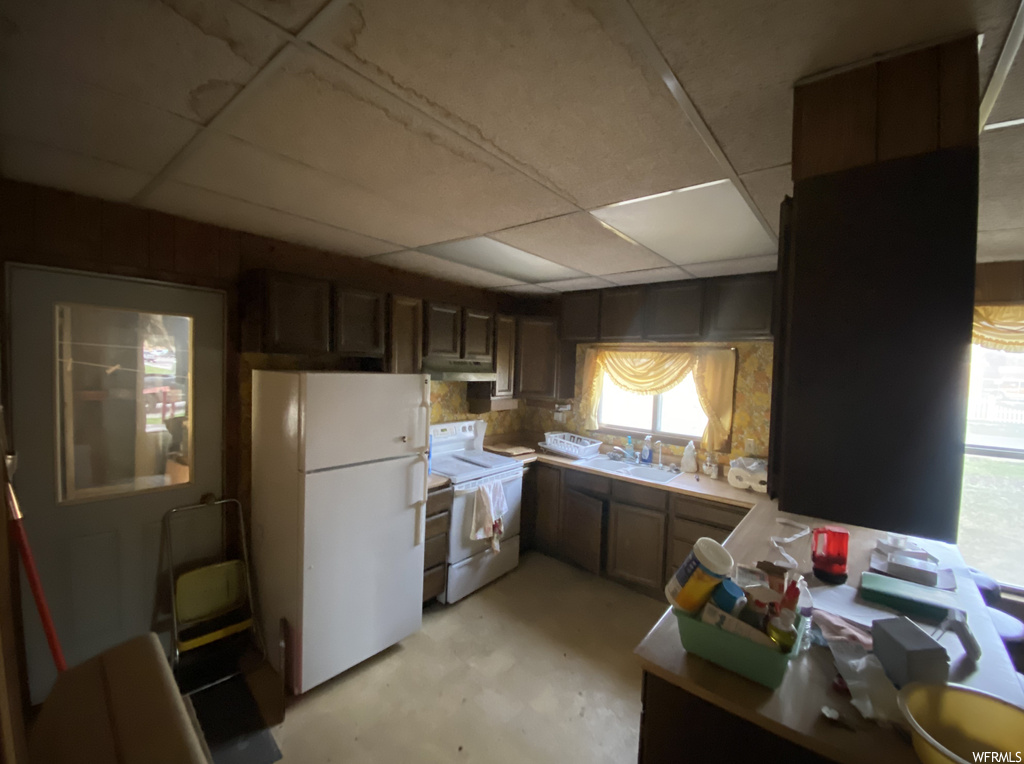 Kitchen with tasteful backsplash, dark brown cabinetry, white appliances, a drop ceiling, and sink