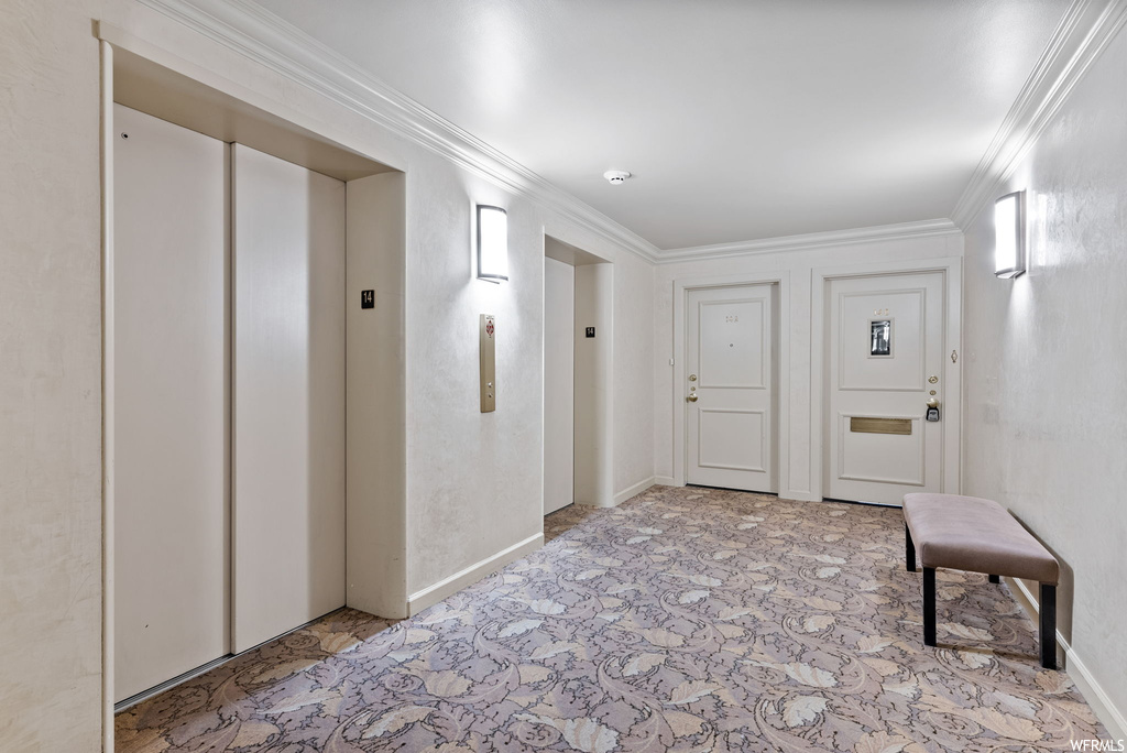 Hall with light tile floors, elevator, and crown molding