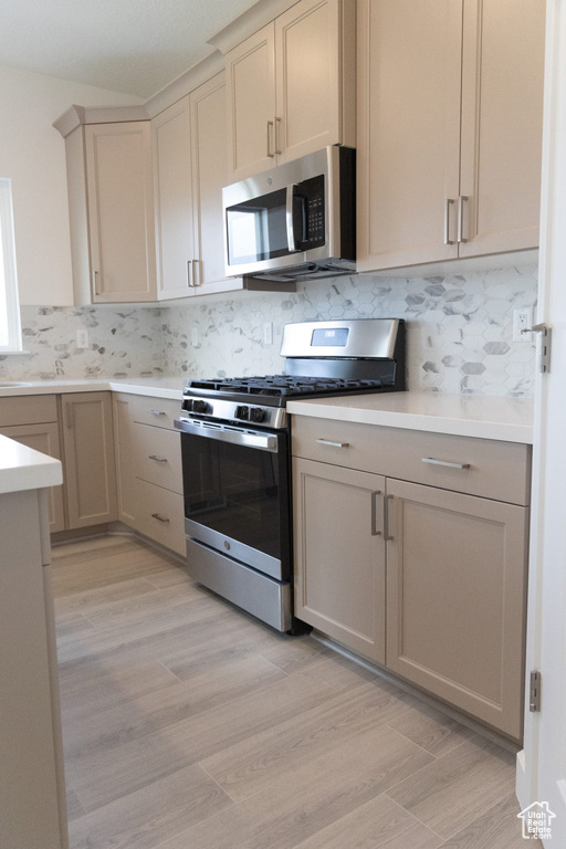 Kitchen with light hardwood / wood-style floors, tasteful backsplash, and stainless steel appliances
