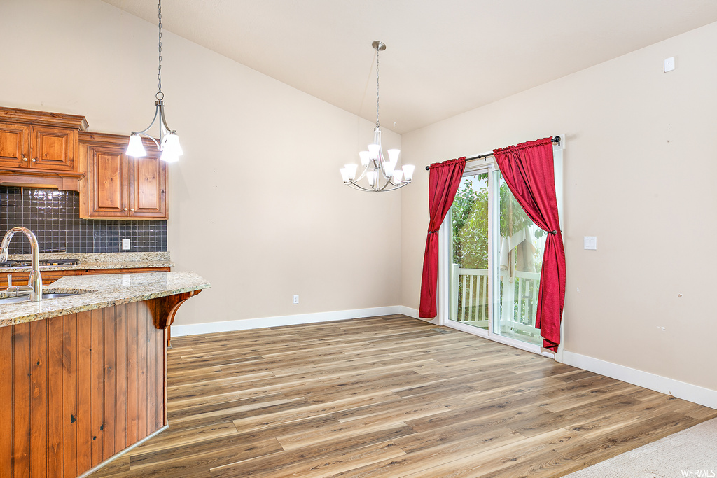 Kitchen featuring backsplash, pendant lighting, light hardwood flooring, and a chandelier
