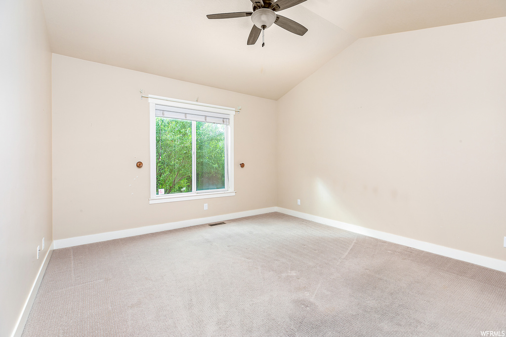 Carpeted empty room with vaulted ceiling and ceiling fan