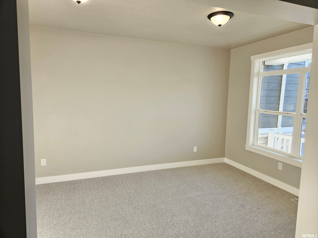 Spare room featuring a textured ceiling and light carpet
