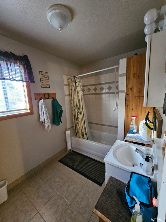 Bathroom with tile flooring, a textured ceiling, sink, and shower / bath combo with shower curtain