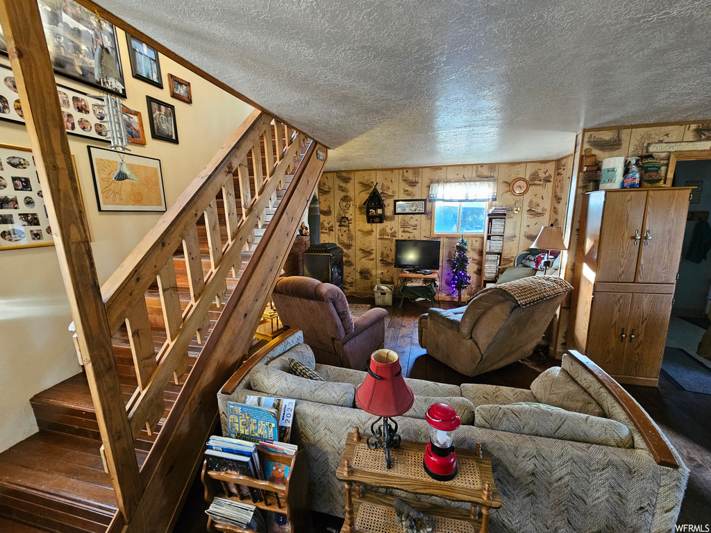 Living room featuring a textured ceiling, wooden walls, and wood-type flooring