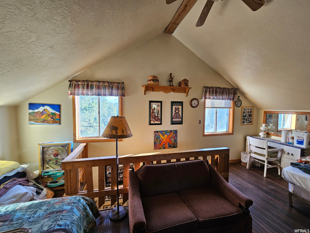 Hardwood floored living room featuring a textured ceiling, vaulted ceiling, and ceiling fan