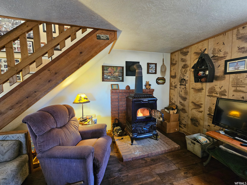 Hardwood floored living room with a wood stove and a textured ceiling