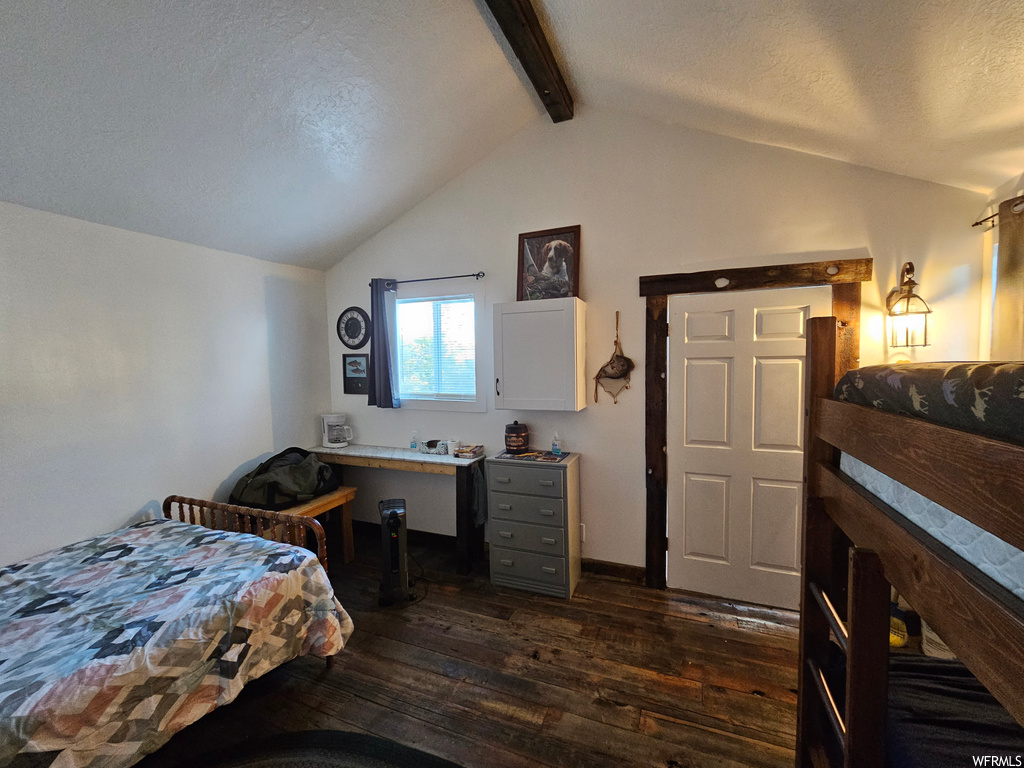 Bedroom with dark hardwood floors, lofted ceiling with beams, and a textured ceiling