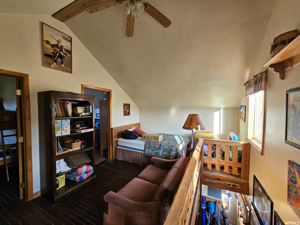 Bedroom featuring ceiling fan, dark hardwood floors, vaulted ceiling, and a textured ceiling