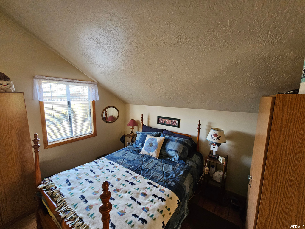 Bedroom featuring a textured ceiling and lofted ceiling