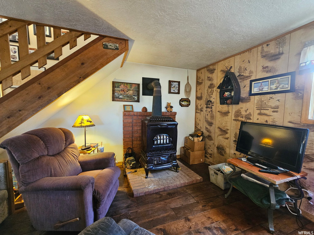 Living room with dark hardwood flooring, a wood stove, and a textured ceiling