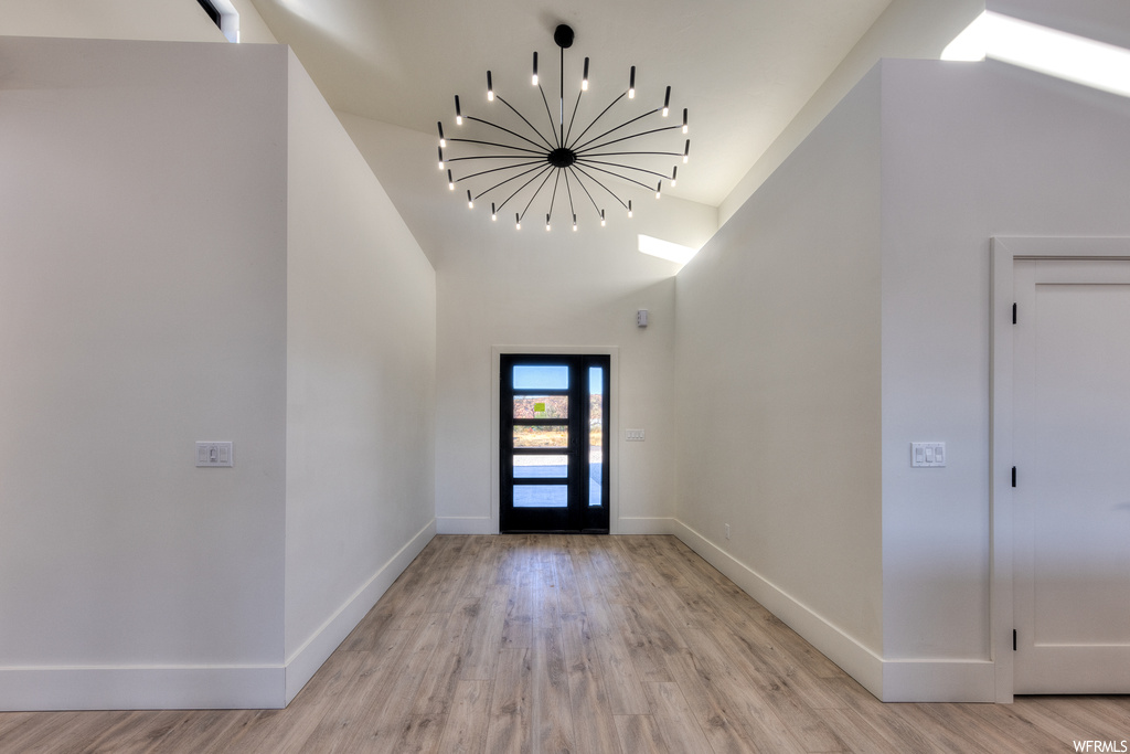 Foyer featuring a chandelier, light hardwood flooring, and lofted ceiling