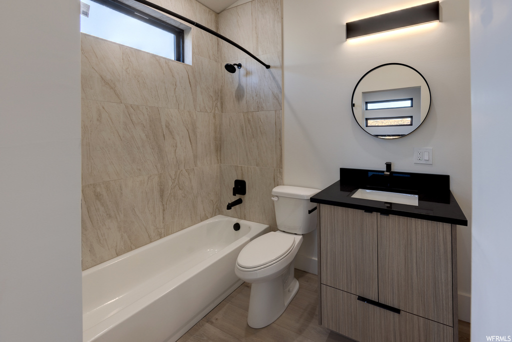Full bathroom featuring toilet, oversized vanity, and tiled shower / bath combo