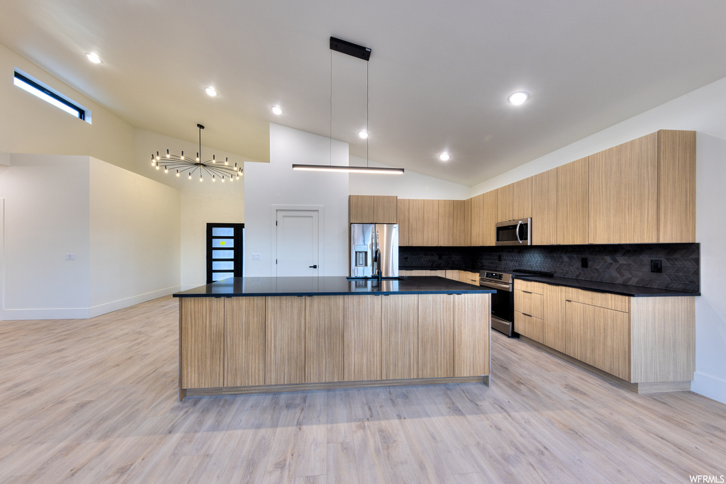 Kitchen featuring a center island, stainless steel appliances, light hardwood floors, and decorative light fixtures