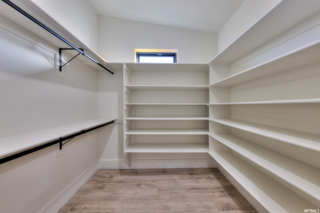 Walk in closet with vaulted ceiling and light hardwood flooring