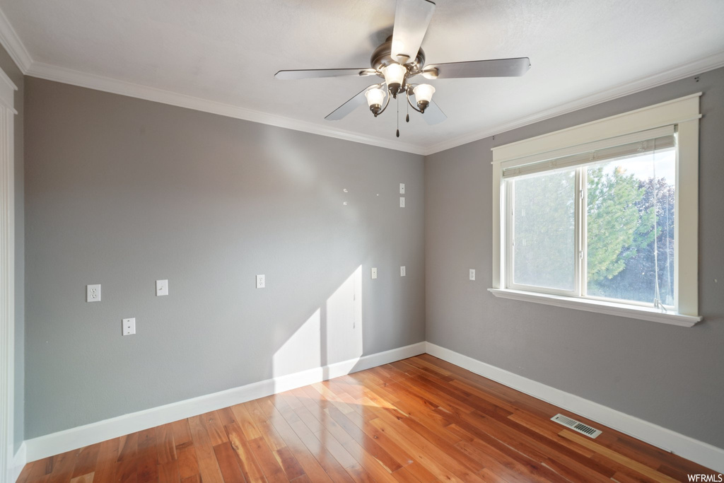 Spare room with crown molding, light hardwood flooring, and ceiling fan