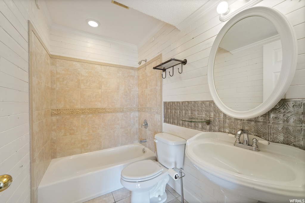 Full bathroom with sink, tiled shower / bath, tile floors, and toilet