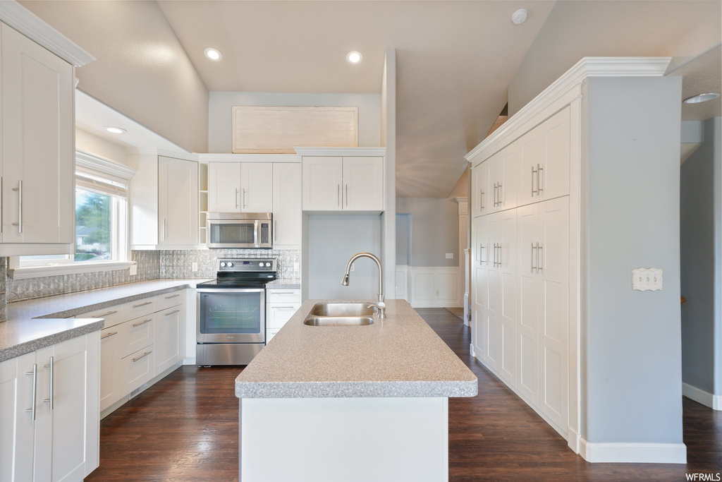 Kitchen featuring a center island with sink, stainless steel appliances, dark hardwood floors, and sink