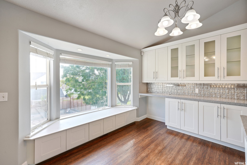 Kitchen featuring white cabinetry, dark hardwood floors, decorative light fixtures, and plenty of natural light