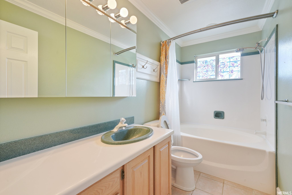 Full bathroom featuring toilet, shower / bath combination with curtain, crown molding, tile floors, and vanity with extensive cabinet space
