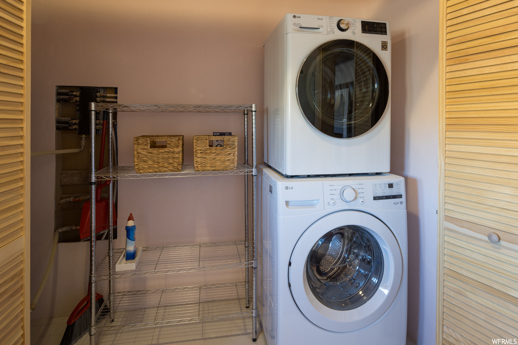 Clothes washing area with stacked washer and dryer and light tile floors