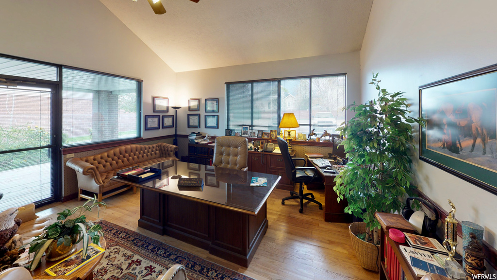 Hardwood floored home office featuring a wealth of natural light, vaulted ceiling high, and ceiling fan