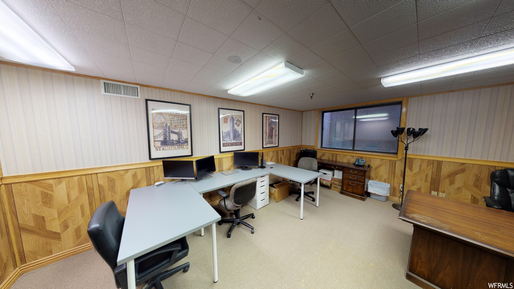 Carpeted office space featuring wood walls and built in desk