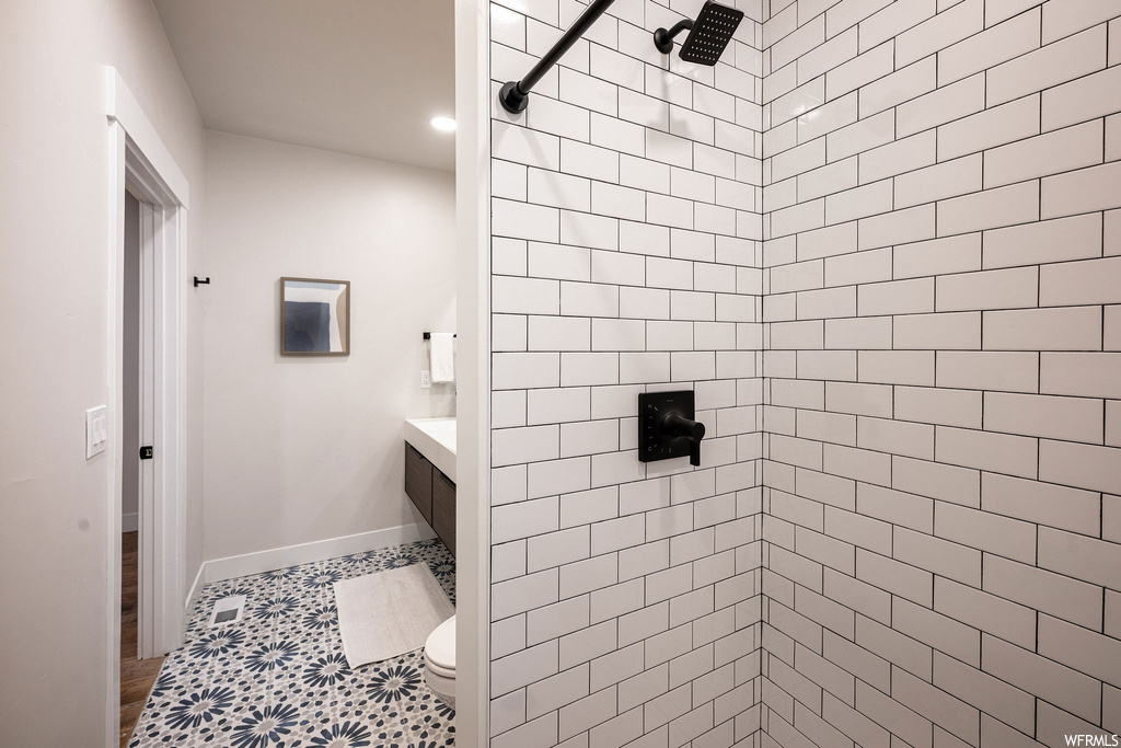 Bathroom with a tile shower, tile flooring, and toilet