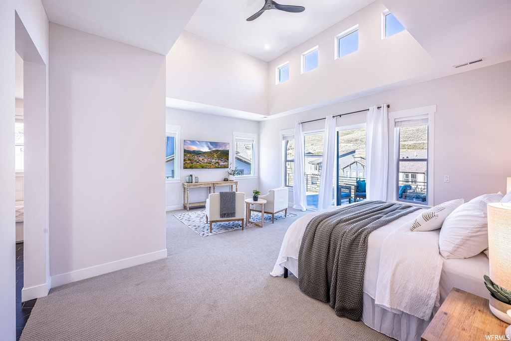 Bedroom with multiple windows, light colored carpet, ceiling fan, and access to outside