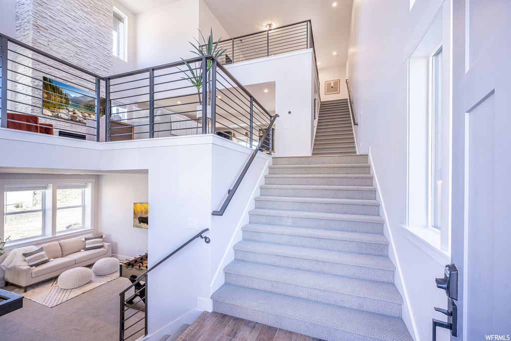 Stairway with a towering ceiling and light hardwood floors