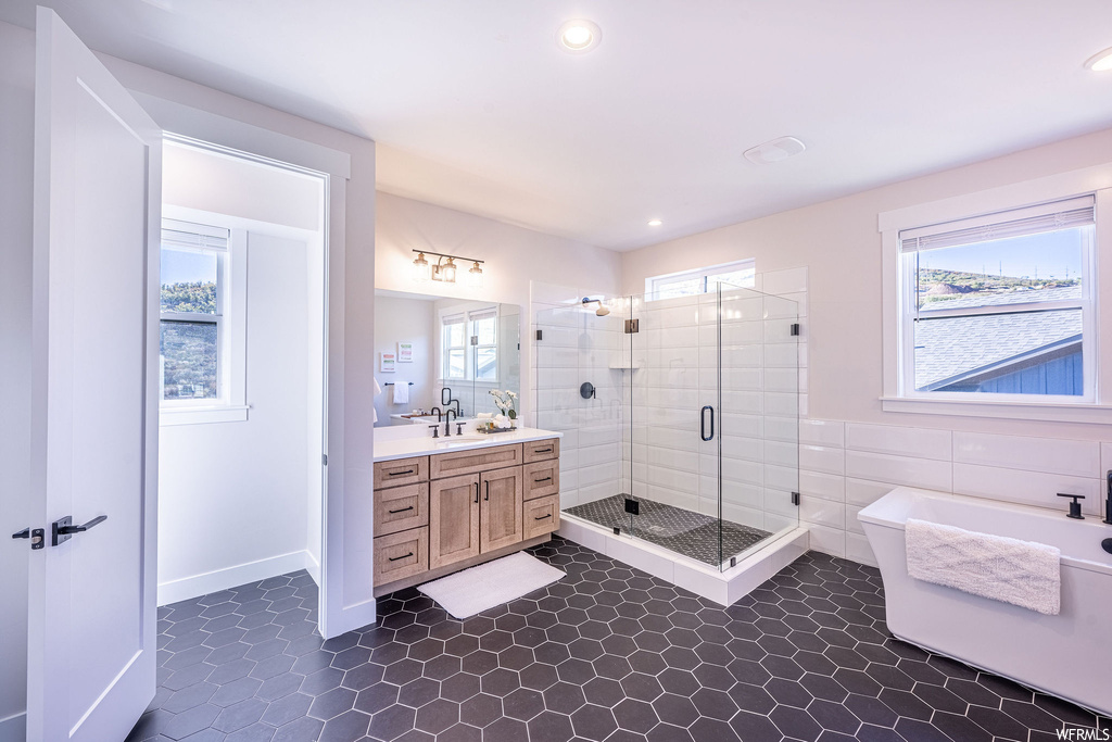 Bathroom featuring tile floors, oversized vanity, independent shower and bath, and a wealth of natural light