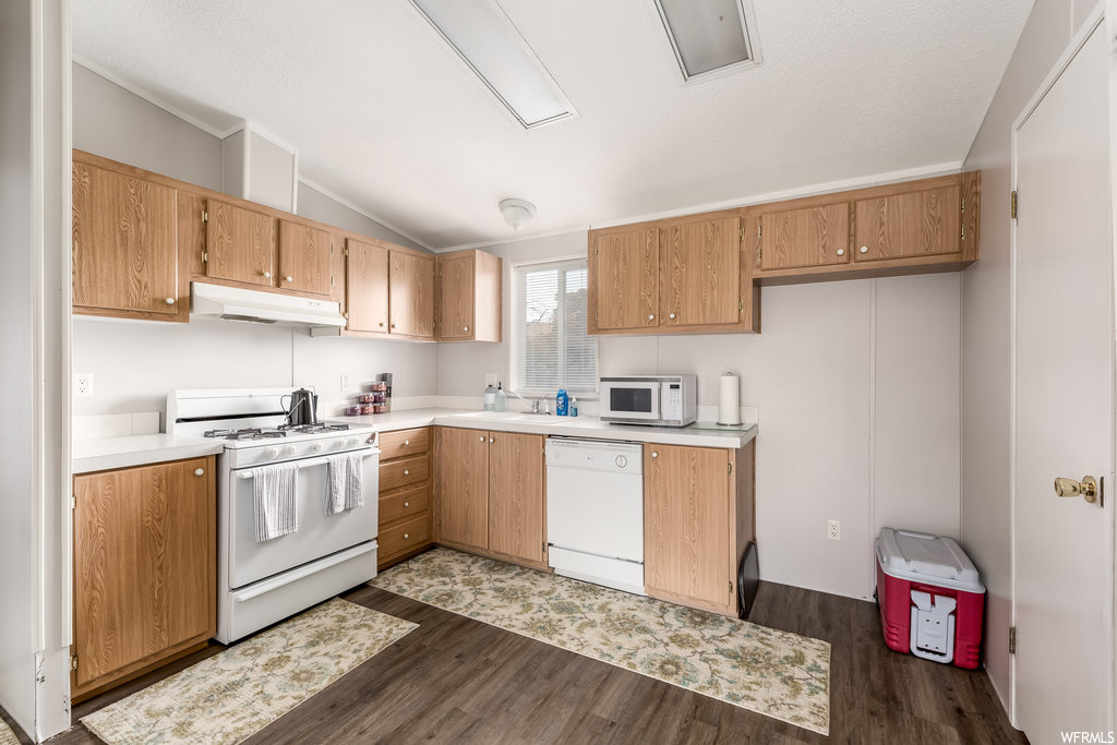 Kitchen featuring white appliances, dark hardwood flooring, sink, and lofted ceiling
