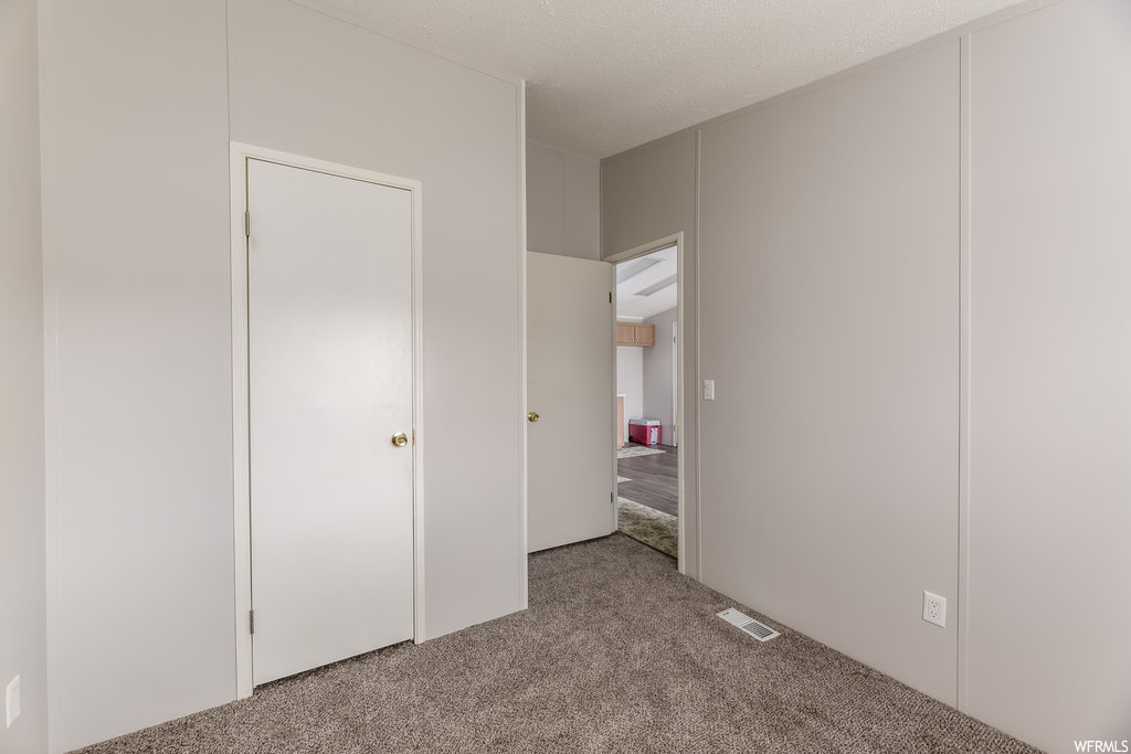 Unfurnished bedroom featuring light colored carpet and a textured ceiling
