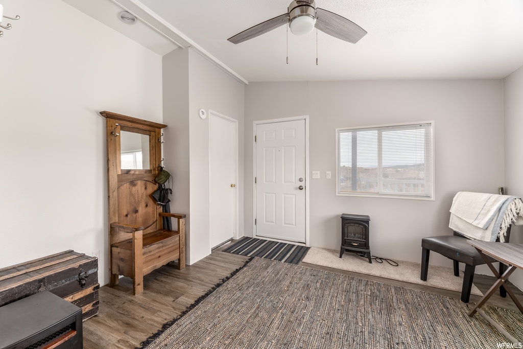 Hardwood floored entryway featuring lofted ceiling, a wood stove, and ceiling fan