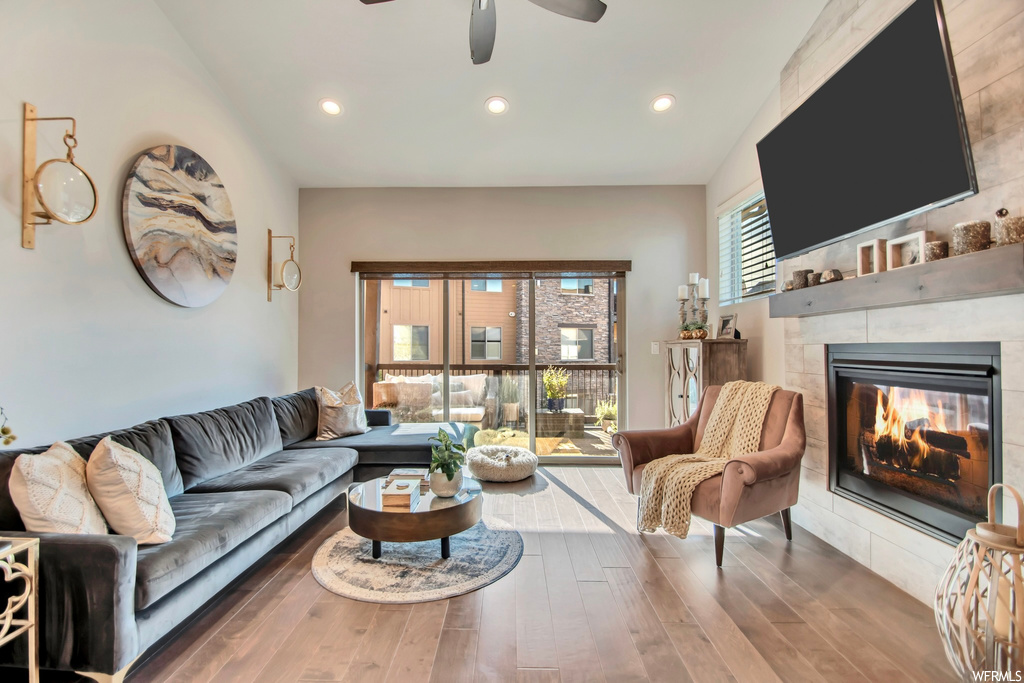 Hardwood floored living room with ceiling fan and a fireplace