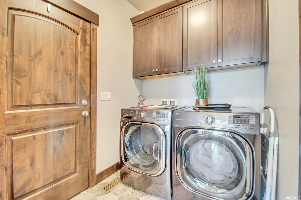 Laundry area featuring hookup for a washing machine, cabinets, light tile floors, and washing machine and dryer