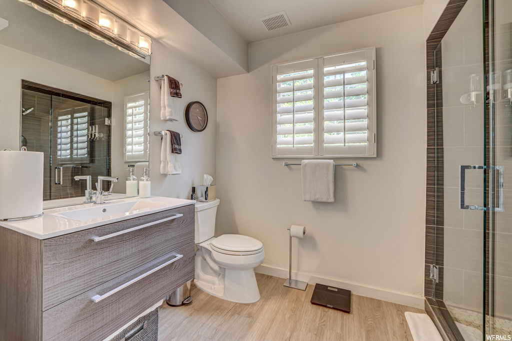 Bathroom featuring walk in shower, toilet, hardwood flooring, and large vanity