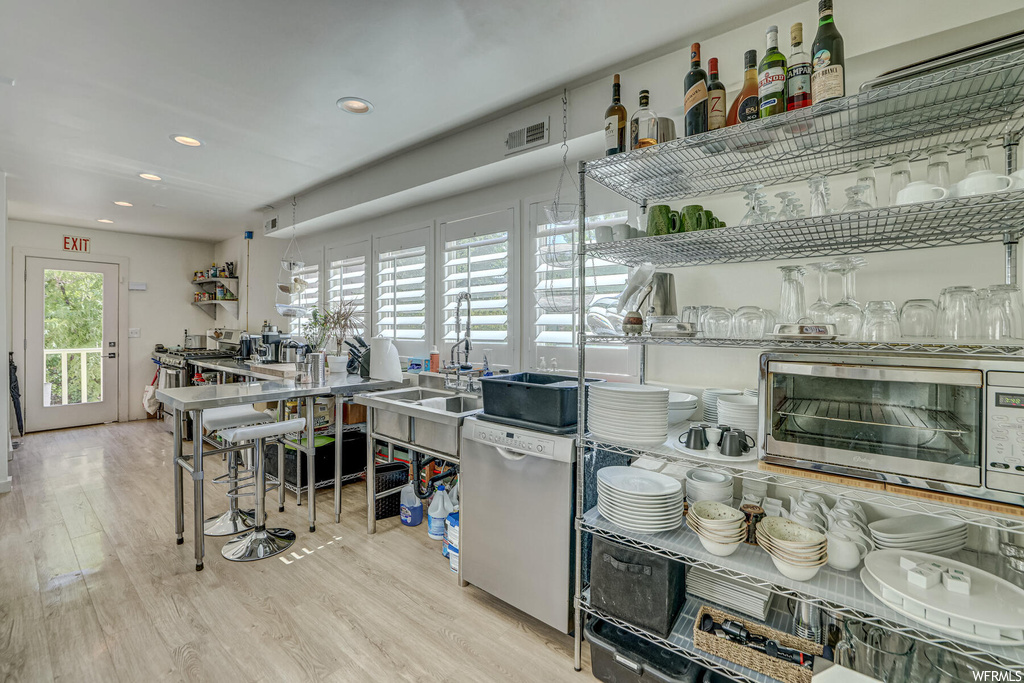 Kitchen with light stone countertops, dishwasher, and light hardwood floors