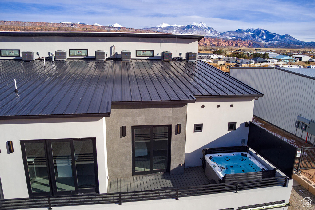 Exterior space with a mountain view, a covered hot tub, and central AC