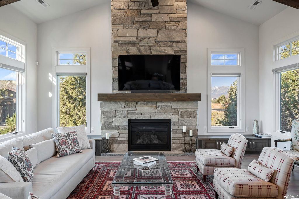 Living room featuring a healthy amount of sunlight, a fireplace, and vaulted ceiling high