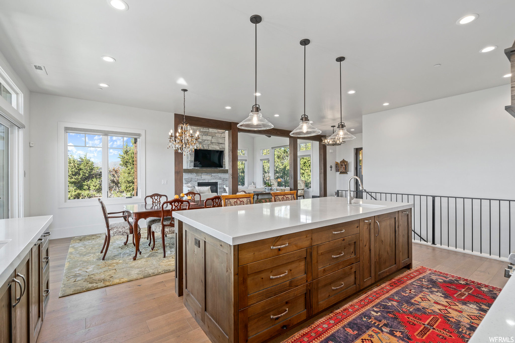 Kitchen with plenty of natural light, a notable chandelier, a fireplace, and light hardwood floors