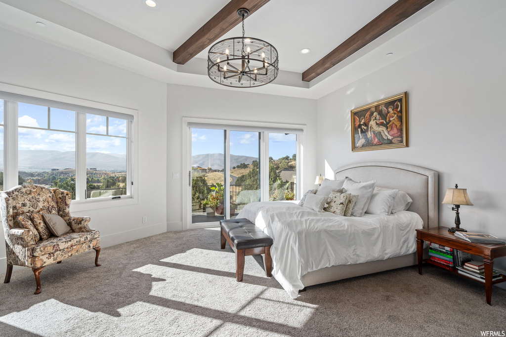 Bedroom with carpet floors, a raised ceiling, an inviting chandelier, and a mountain view